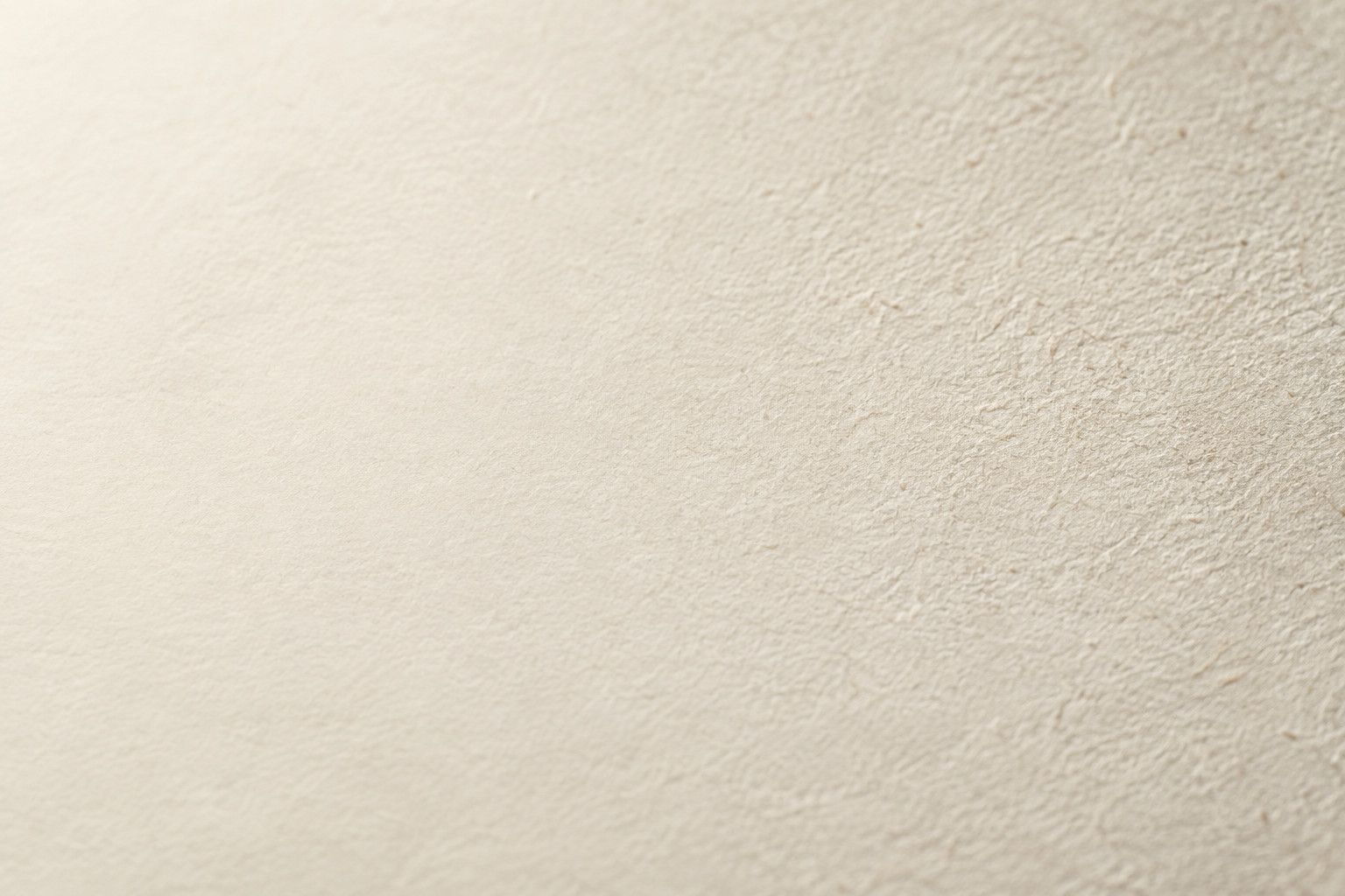Low-angle editorial view of unprinted fine art paper in grazing light